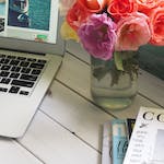 Assorted-color Flower Arrangement in Clear Glass Vase Beside a Laptop